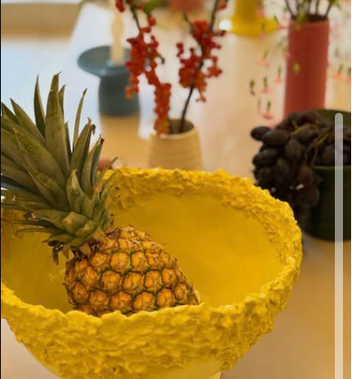 A yellow ceramic bowl and branch arrangements on a table