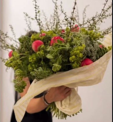 An armful of green branches and coral blooms